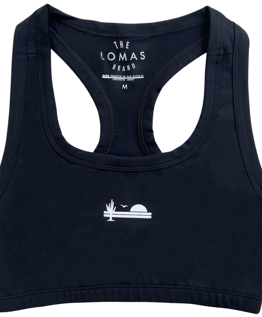 Flat shot of a black sports bra with a white icon showing a saguaro cactus, a bird, and a rising sun in white.