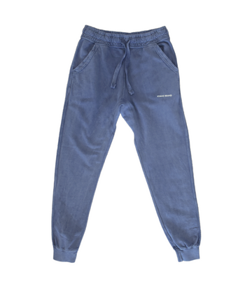 Faded blue sweatpants made of heavyweight yet comfortable material with a relaxed silhouette. The cuffed ankles create a jogger-inspired look. An adjustable drawcord waistband ensures a secure, personalized fit. The front of the pants have 'Lomas Brand' written in all caps in white just below the left pocket.