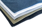 Close up of assorted colored shirts (white, blue, army green, navy, grey, and black) folded.