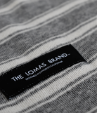 Close up of a grey and white blanket patch that says "THE LOMAS BRAND" with "DESIGNED IN SAN DIEGO CALIFORNIA" underneath.