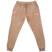 Tan-colored joggers laid flat. The pants have an elastic waistband with a drawstring, side pockets, and tapered legs with elastic cuffs at the ankles. The "LOMAS BRAND" logo is visible on the left thigh area.