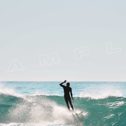 A silhouette of a surfer riding a large wave, with water spraying behind them. The ocean and sky are visible in the background. The word "SAMPLE" is overlaid on the image.