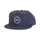 A flat brimmed navy hat with a circular white logo in the middle. The logo features a saguaro cactus, a flying bird, and a rising sun inside lettering that says "THE LOMAS BRAND."